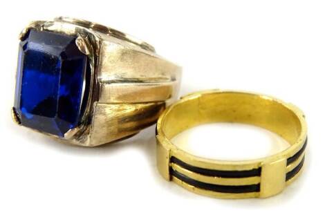 Two modern dress rings, one set with blue paste stone, in silvered colour band, unmarked and another gold plated with enamel decoration. (2)