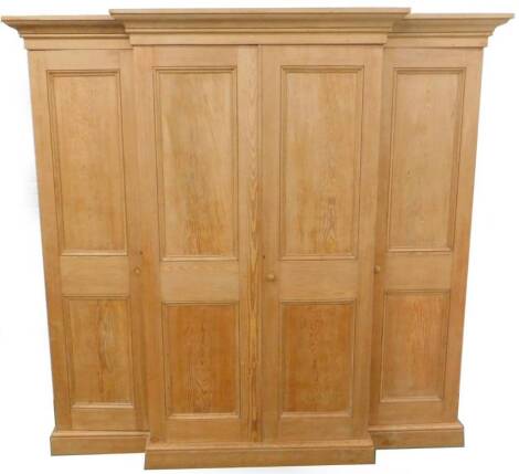 A Victorian stripped pine breakfront wardrobe, with two panelled doors, flanked by two further doors, to each side on a plinth base, 224cm H, 62cm D, 135cm W.