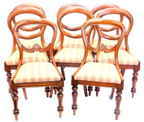 A harlequin set of eight Victorian mahogany balloon back dining chairs, each with a drop in seat upholstered in striped fabric, on turned legs.