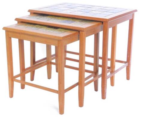 A nest of three G plan type teak retro tables, each inset with oriental style green and brown ceramic tiles, on square tapering legs, the largest 57cm W.