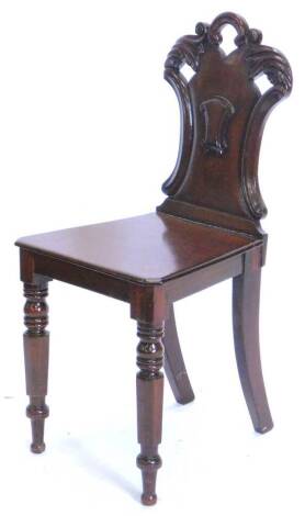 A Victorian mahogany hall chair, with a carved pierced shield shaped back, a solid seat on turned tapering legs.