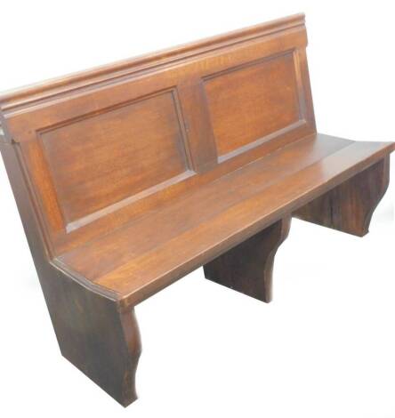 An oak pew section, with a panel back and solid seat on shaped supports, 136cm W.