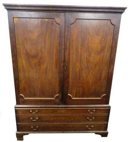 A George III mahogany clothes press, the top with a blind fret cornice above two panelled doors enclosing a partly fitted interior, the base with a double sized long drawer and a regular drawer, on bracket feet, adapted (AF), 203cm H.