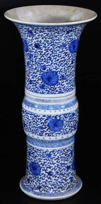 A Chinese porcelain blue and white beaker vase, with flared base and neck, decorated with scrolling lotus designs in underglaze blue, between Greek key fret, scroll and dot bands, glazed base with double ring and two character mark, 19thC, 45cm H.