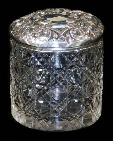 An Edwardian silver and cut glass jar and cover, the lid profusely repousse decorated with scrolls and birds, Birmingham 1905, 8cm H.