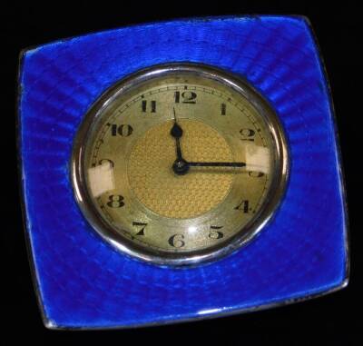 An early 20thC enamel travel clock, with 4cm Dia. Arabic dial, on a fancy hammered back, marked enamelled on sterling silver, 7cm H.