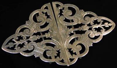 A Victorian silver double nurse's buckle, of shaped mitre outline, partially pierced and etched with scrolls, with plain pin backs to each section, 6cm W, 1oz. (2)