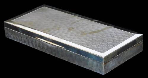 An Elizabeth II silver table cigarette box, of low rectangular design, with hinged lid and having beaten effect decoration, Birmingham 1973, 22.2cm H, 9.9cm W, 3cm D.