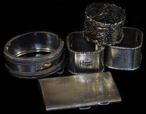 A pair of silver napkin rings, with engraved initials and engine turned decoration, Birmingham 1933, 2.29oz, another silver napkin ring, Victorian silver hinged bangle and a ladies silver cigarette case, Birmingham 1936, 5.80oz total weight.