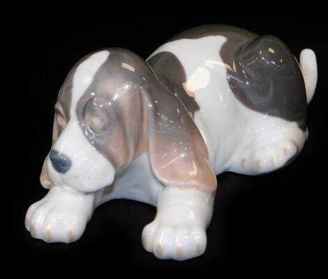 A Lladro figure of a sleeping Bassett hound, printed marks beneath, 6cm H.