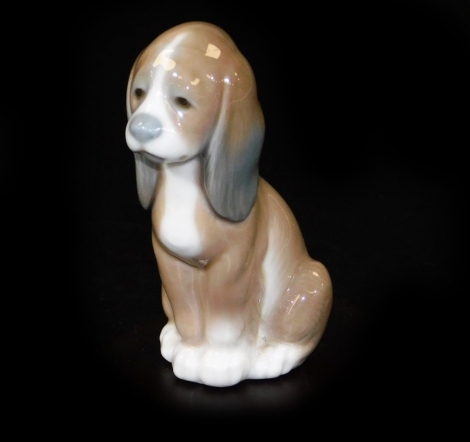 A Lladro figure of a seated dog, on wooden base, printed marks beneath, 10cm W.