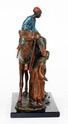 A cast and painted spelter figural table lighter, in the manner of Bergmann, formed as an Arabian rug seller on a camel's back, aside a further figure, on a rectangular base, 19cm H. (AF) - 2