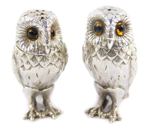 A pair of novelty silver owl salt and pepper shakers, each modelled standing, set with orange glass eyes, Richard Comyns, London 1970, 4.38oz.