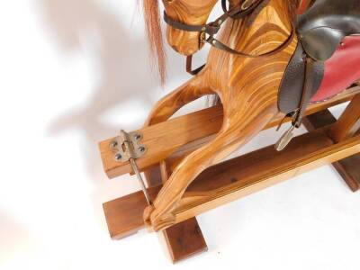 A marquetry and pine rocking horse, with red and brown leather saddle, and metal stirrups, 102cm H, 179cm W. - 2