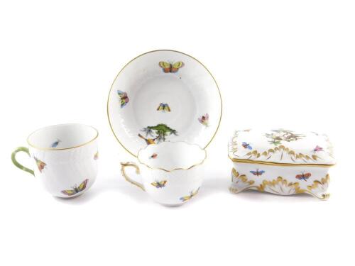 A Herend porcelain dressing table box and cover, of rectangular form, traditionally decorated with birds, butterflies and insects, raised on four scroll feet, 11.5cm W, together with a coffee cup and saucer, and a further coffee cup. (4)