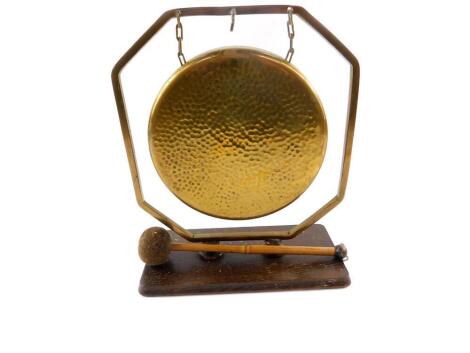 An early 20thC brass gong, in an octagonal frame, raised on a rectangular oak base, with clanger, 22cm W.