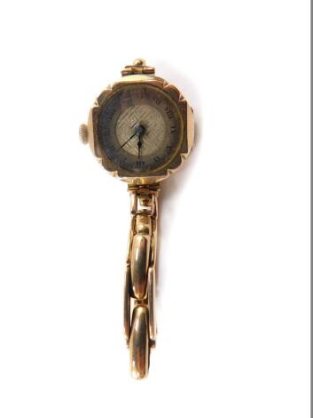 A mid 20thC lady's 9ct gold cased wristwatch, circular silver dial with engine turned decoration, chapter ring bearing Roman numerals, Swiss fifteen jewel movement, the case of shaped circular form on a yellow metal elasticated bracelet, stamped 9ct, 18.5