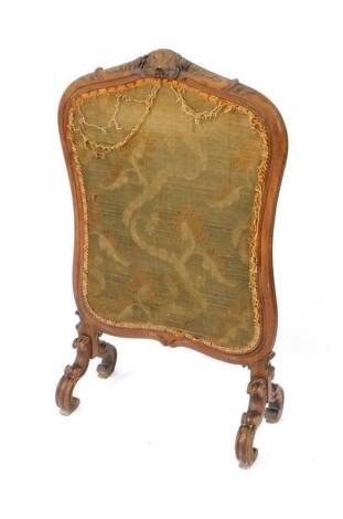 A Victorian mahogany fire screen, fabric in a shield shaped frame, carved with a shell flowers and leaves, raised on four fluted scroll feet, 106cm H, 64cm W.