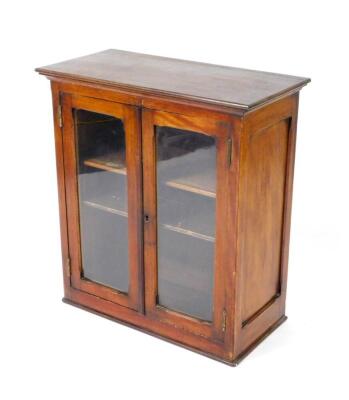 A Victorian mahogany display cabinet, the outswept pediment over two glazed doors enclosing two glazed shelves, raised on a plinth base, 74cm H, 67cm W, 33cm D.