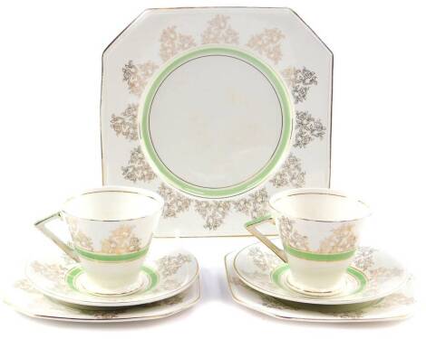 A pair of Art Deco porcelain trios, decorated with gilt floral sprays and green bands, together with a bread plate. (7)