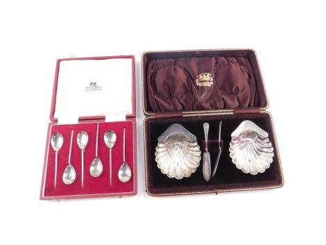 A pair of George V silver butter dishes, of scalloped shell form, raised on three ball feet, with knives, cased, London 1913, together with six silver coffee spoons, cased, Sheffield 1971, 4.67oz.