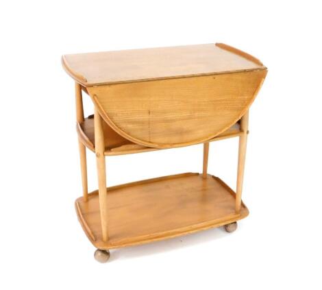 An Ercol light elm three tier trolley, the top with drop flaps, raised on turned supports, on castors, 75cm H, 73cm W, 44cm D, top 96cm extended.