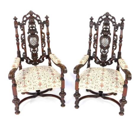 A pair of 19thC Carolean style walnut armchairs, with foliate carved crest rail and foliate and pierced lattice splat, flanked by fluted and turned columns, leaf scroll arms with over stuffed arm rests, and over stuffed seats, raised on turned and fluted 