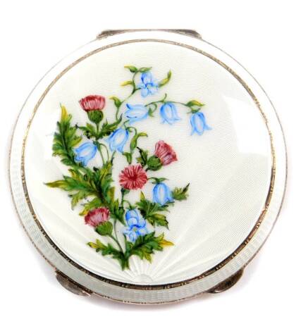 A silver and guilloche enamel compact, the lid with a sunburst design over painted with thistles and blue lily of the valley, Birmingham 1959, 3.75oz.