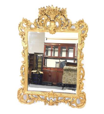 A Rococo style giltwood rectangular wall mirror, inset bevelled glass, with pierced foliate scrolls, the crest rail with basket of flowers surmount, 130cm H, 89cm W.