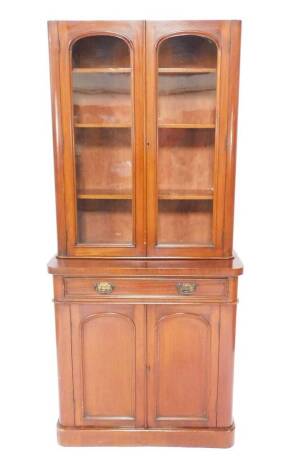 A Victorian mahogany bow front cupboard bookcase, pediment lacking, with two glazed doors, opening to reveal three shelves, over a frieze drawer, above a pair of doors, enclosing a further shelf, raised on a plinth base, 193cm H, 88cm W, 40cm D.