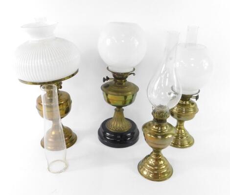 A Duplex brass oil lamp, with glass chimney and fluted white glass shade, 52cm H, brass oil lamp with a white glass shade, raised on a black pottery socle, 48.5cm H, further brass oil lamp, with a glass chimney and white glass shade, 49cm H, a Swan Brand 