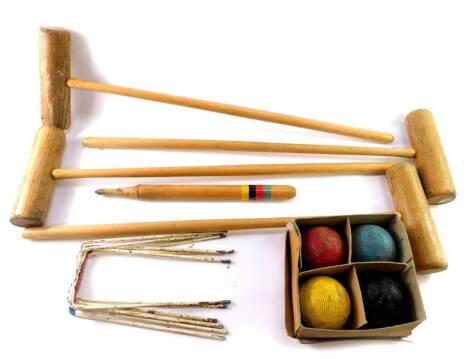 A croquet set, comprising four wooden mallets, four balls, centre peg, and six metal hoops, boxed.