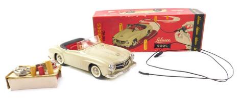 A Schuco 2095 tinplate clockwork remote control Mercedes-Benz 190sl, cream body and red plastic interior, with key, steering wheel control cable and five bollards, boxed. (A/F)