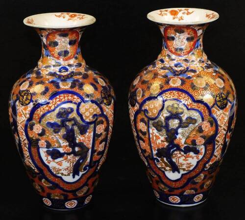 A pair of Meiji period Japanese Imari vases, each of baluster form, profusely decorated with panels, scrolls and flowers in orange and blue with gilt highlights, 30cm H. (2)