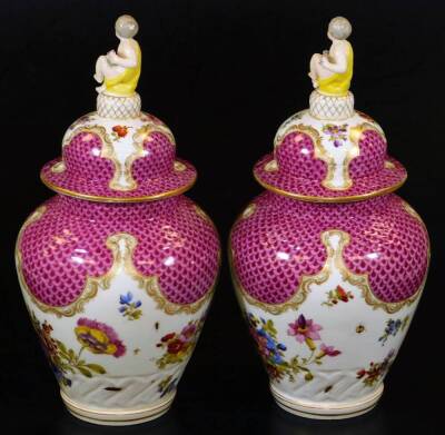 A pair of Meissen porcelain vases and covers, each exquisitely decorated with flowers, with domed circular lids surmounted by cherub and garland finials, each main body decorated with feathered pink and purple panelling, with further handpainted flowers o - 2