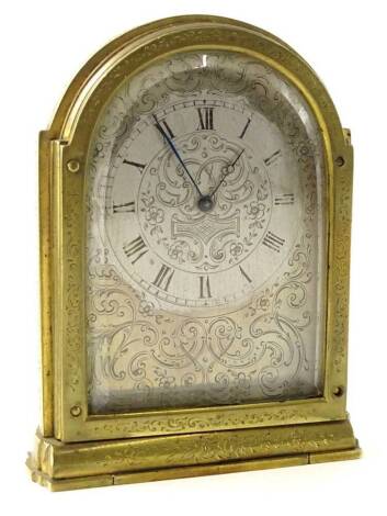 A 19thC engraved brass travelling clock in the manner of Thomas Cole, the arched silvered dial decorated with scrolls etc., on a folding base, 9.5cm H.