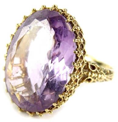 A 9ct gold dress ring, with large central pale purple stone, in multi claw setting, in a raised and pierced basket, ring size S, 11.5g all in.