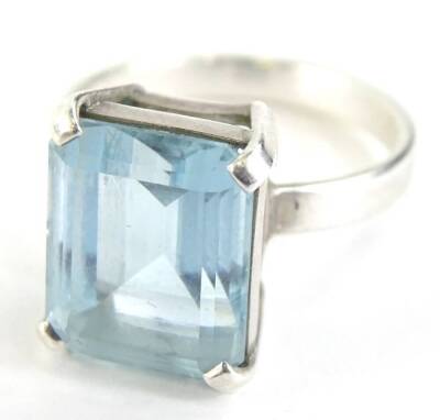 A modern dress ring, with central rectangular cut aquamarine in four claw setting, on a plain white metal band, unmarked, ring size P.