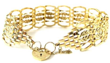 A 9ct gold gate bracelet, of modern five row scroll design, with safety chain and small padlock, 7.3g all in.