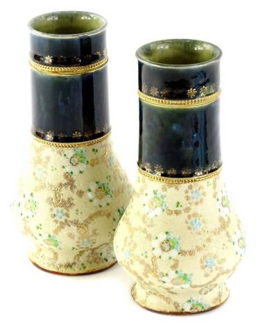 A pair of early 20thC Royal Doulton Slaters patent vases, each of cylindrical bellied form, decorated with flowers on a cream ground with gilt highlights with an upper double gilt banding, impressed marks beneath, 18cm H.