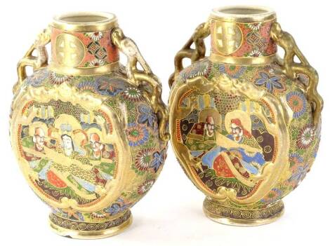 A pair of Japanese Satsuma moon flask vases, each decorated with figures within elaborate scroll and floral pattern on circular feet, with gilt highlights and elaborate dragon handles, 26cm H. (2)