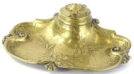 An early 20thC brass inkwell, with shaped tray raised with garlands and shields, with circular well set with hinged lid, 16cm W.
