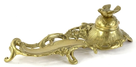 An early 20thC brass inkwell, of pierced and twined form, the well domed lid, set with bird on scroll feet, 25cm W.