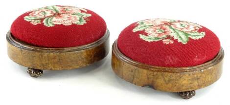 A pair of Victorian walnut foot stools, each with a later woolwork floral padded top, on agate ware lobed feet, 25cm dia.