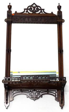 An Edwardian mahogany wall mirror in Chippendale style, with a pierced crest and a blind fret frieze, flanked by cluster columns headed by turned urns, the rectangular bevel plate above a pierced break front shelf above pierced brackets and apron, 35cm W,