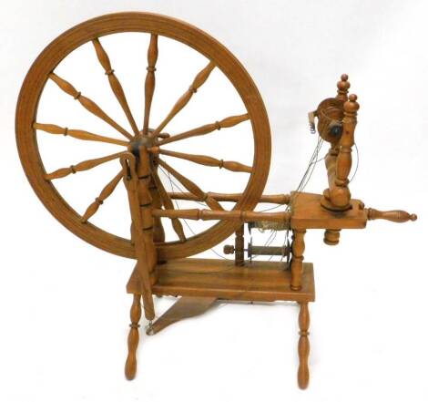 A modern oak spinning wheel, with turned spokes, supports on a rectangular base, 96cm W.