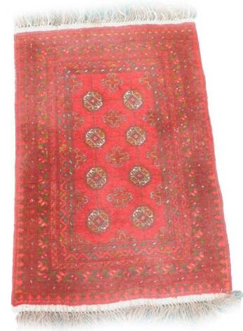 A Persian design rug, with eight medallions on a red ground with multiple borders, 114cm x 80cm.