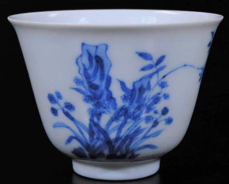 A Chinese porcelain blue and white month cup, with six character Kangxi mark, decorated with orchids emerging from rocks and poem (The delicate fragrance pervades the spacious hall, like music from lofty terraces far away) and seal mark. 5cm H.