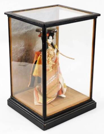 A 20thC Japanese geisha doll, in glazed case, 36cm H, 26cm W, 21cm D.