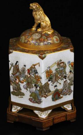 A Japanese Meiji period hexagonal Satsuma koro and cover, with shishi finial, profusely decorated with a continuous scene of figures in flowing robes, beneath mulit-floral band on shaped feet with gilt highlights, signed Kinkozan zo, on wooden stand, 19cm